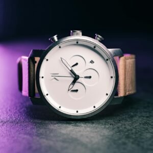 A stylish modern wristwatch with a sleek design, photographed against a dark backdrop.