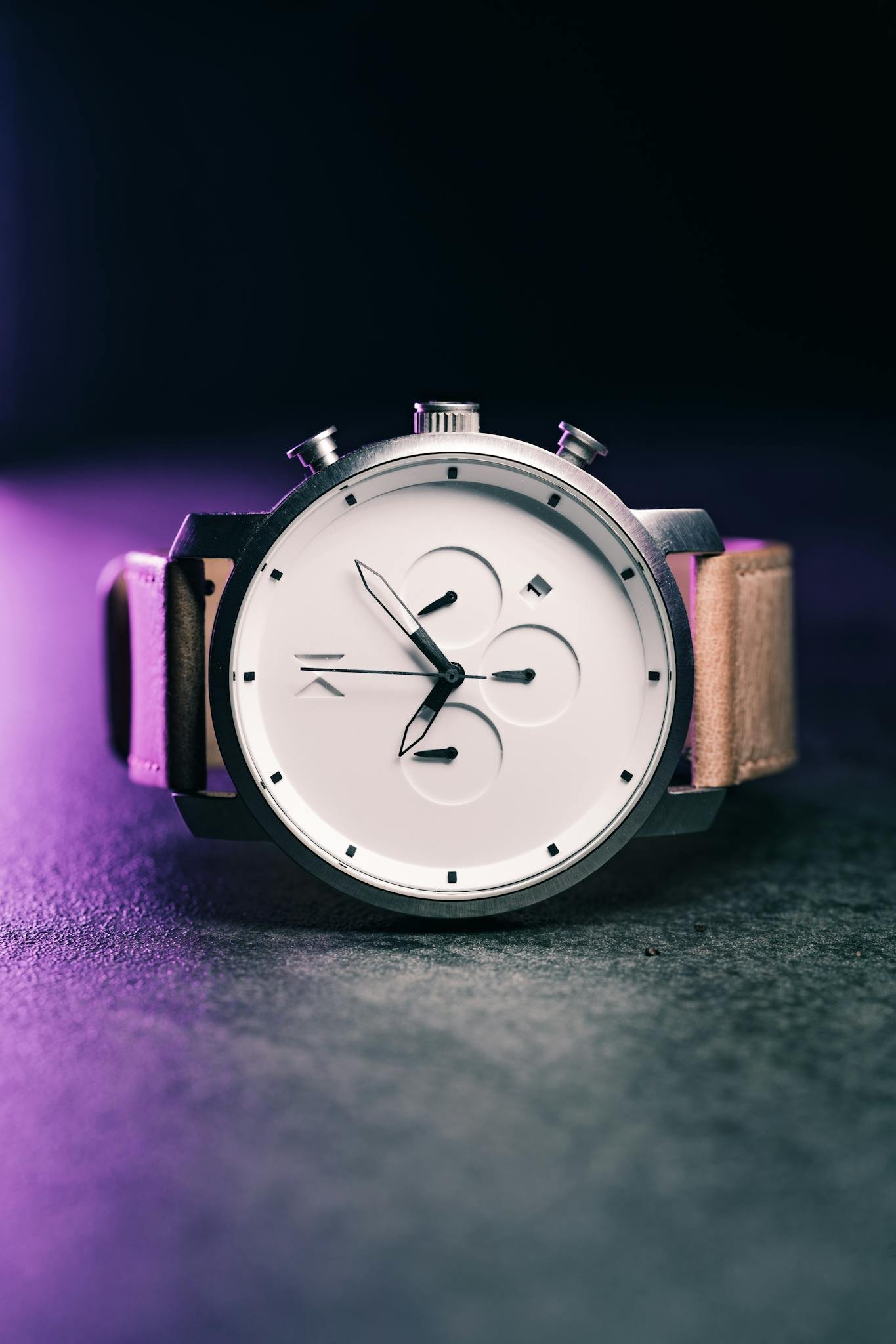 A stylish modern wristwatch with a sleek design, photographed against a dark backdrop.
