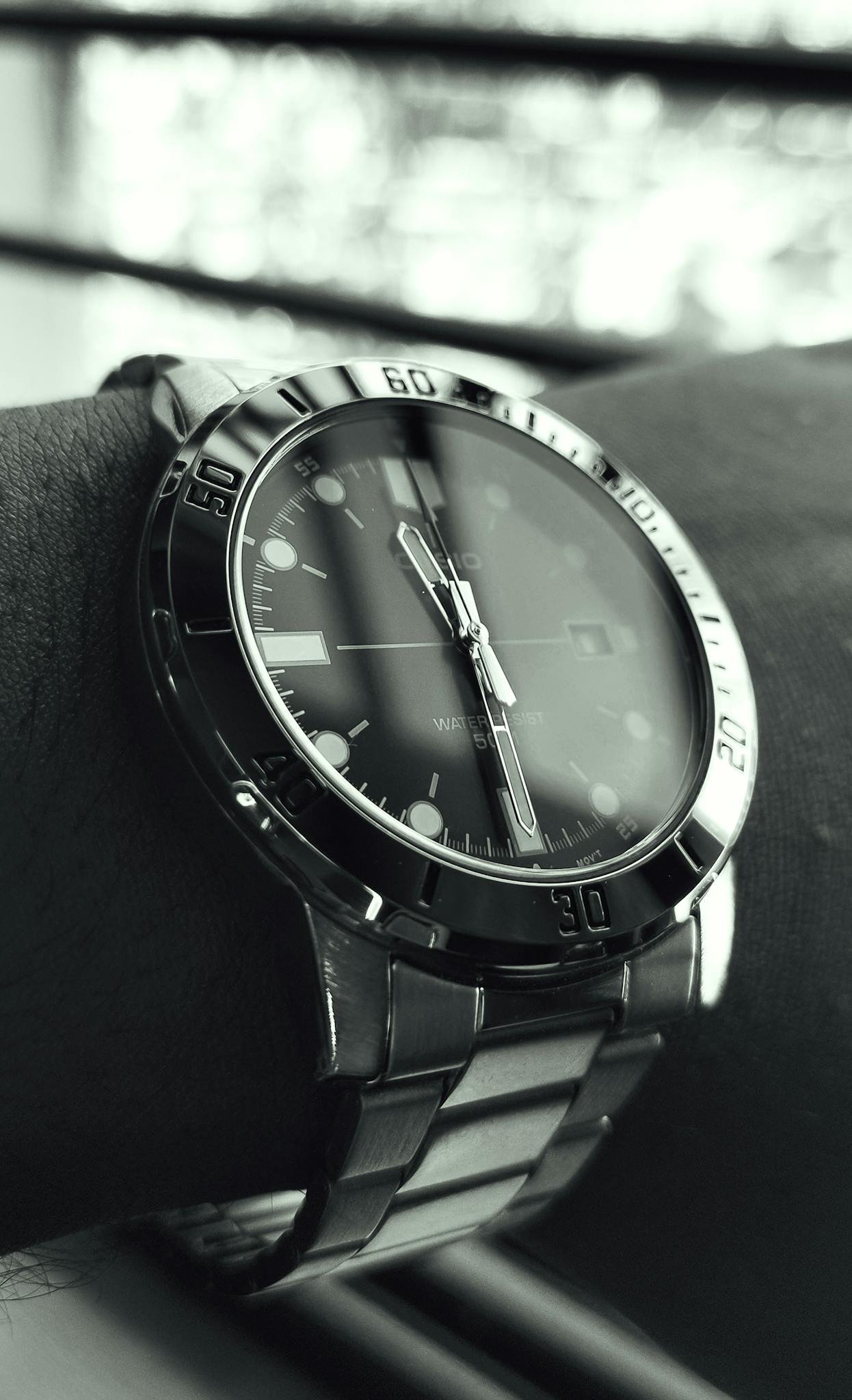 Close-up black and white photo of a stylish wristwatch on a wrist, showcasing design and style.