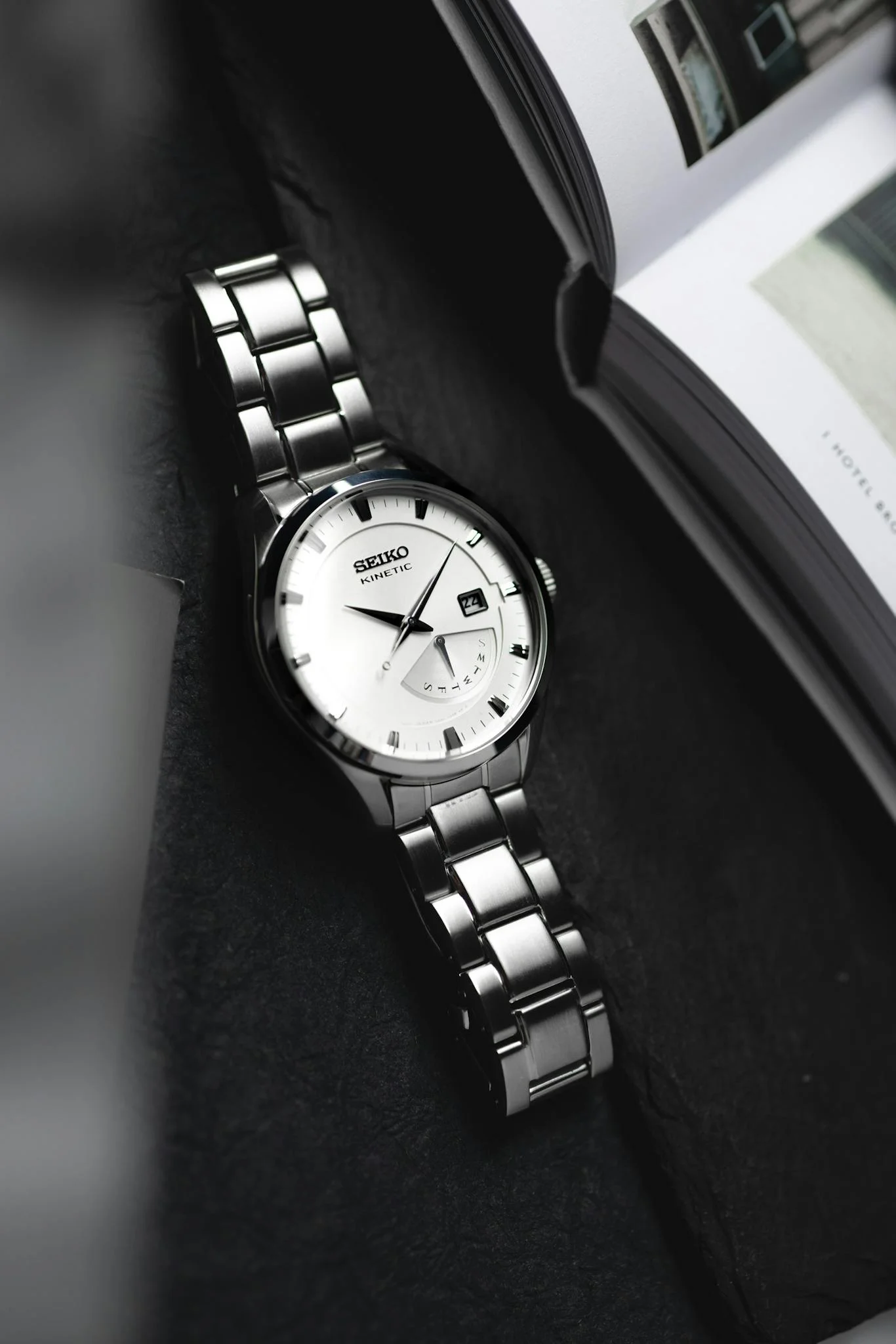 Elegant close-up of a stainless steel Seiko watch with a book in the background.