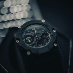 High-contrast close-up of a black wristwatch featuring intricate details against a blurred bokeh background.